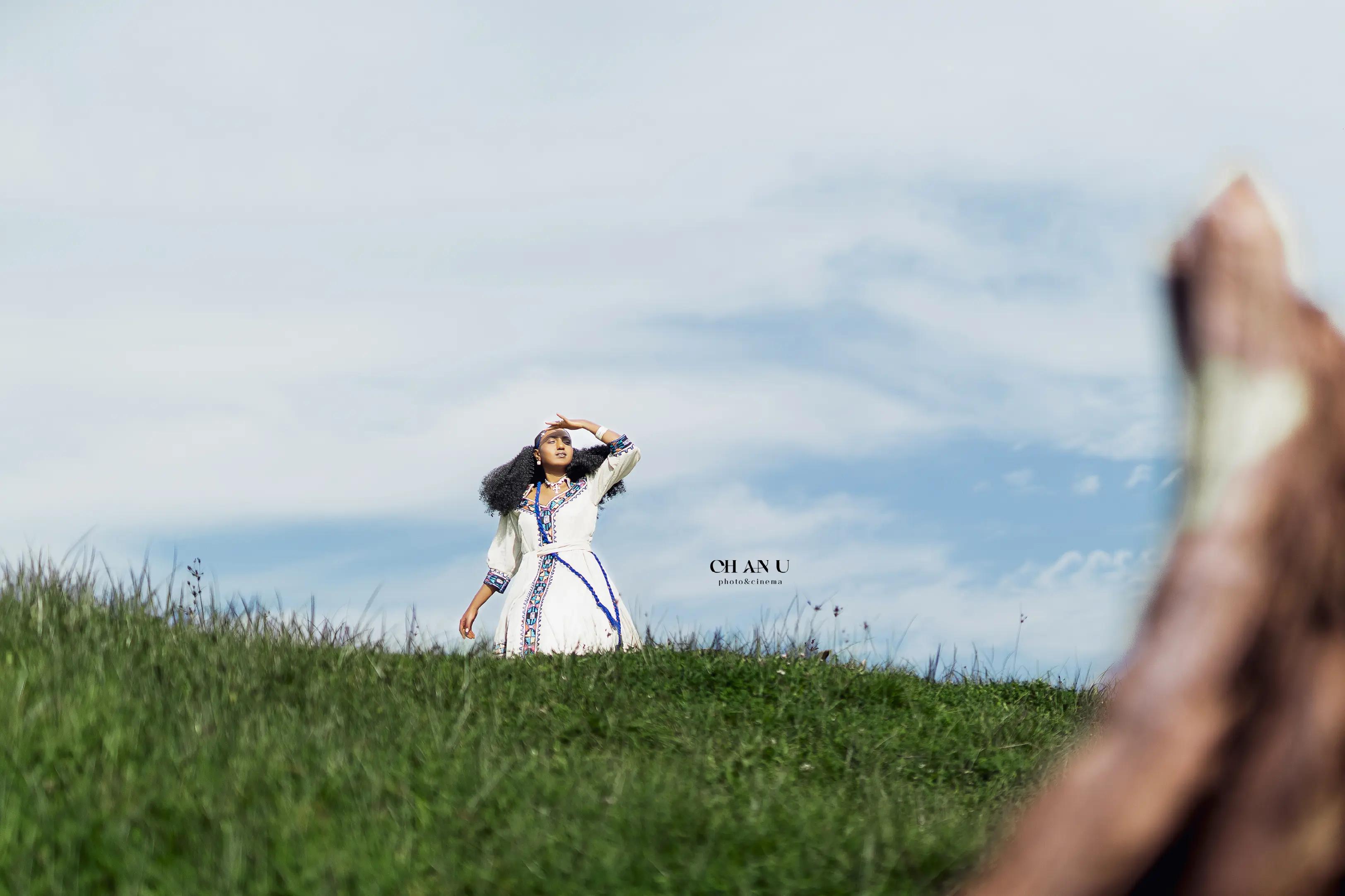 Ethiopian woman in traditional habesha kemis on hillside