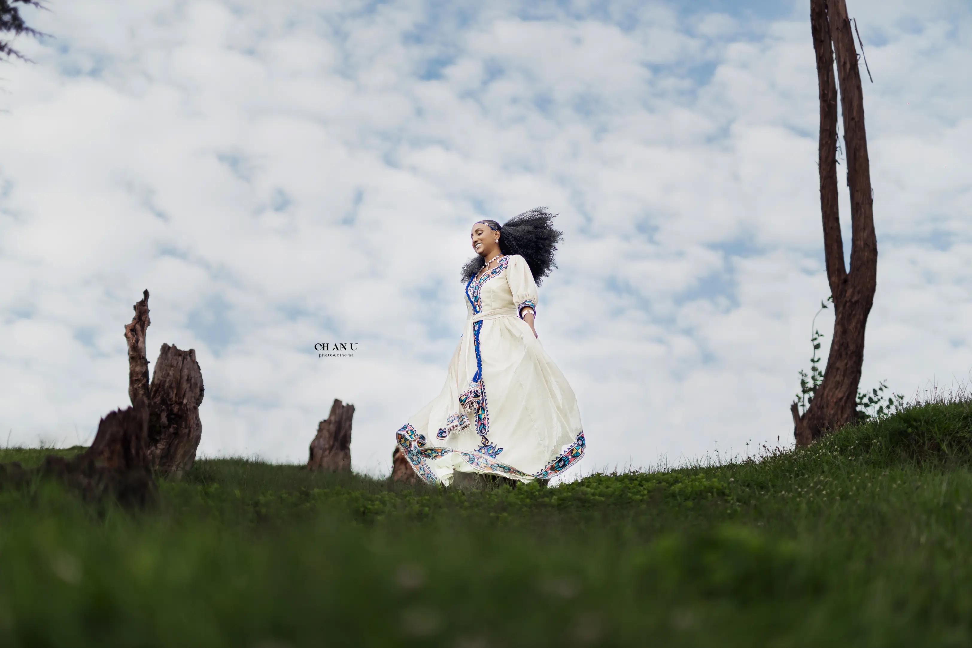 Ethiopian woman in white habesha dress in open field