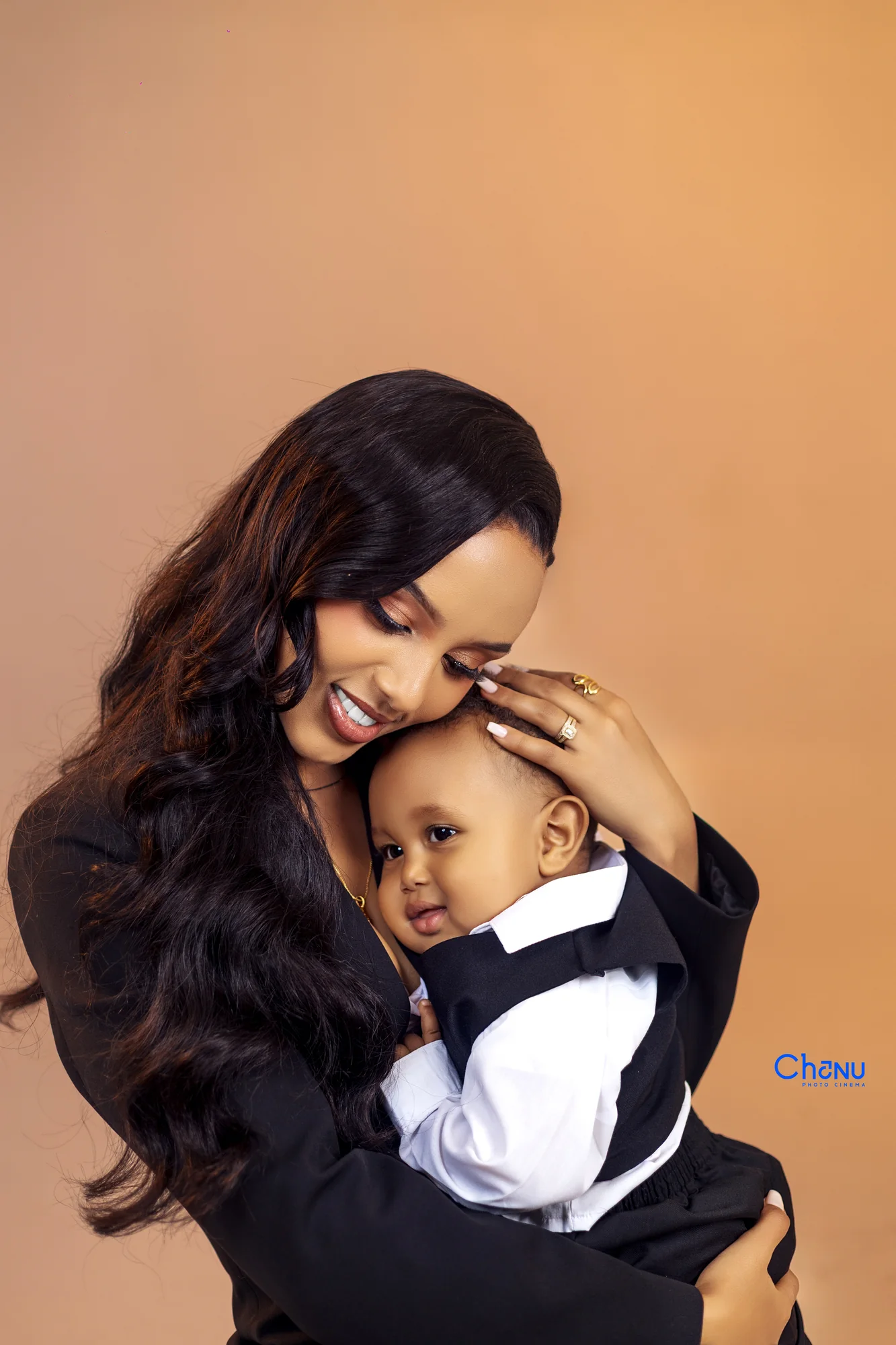 Intimate studio milestone portrait of mother holding baby boy in tuxedo suit