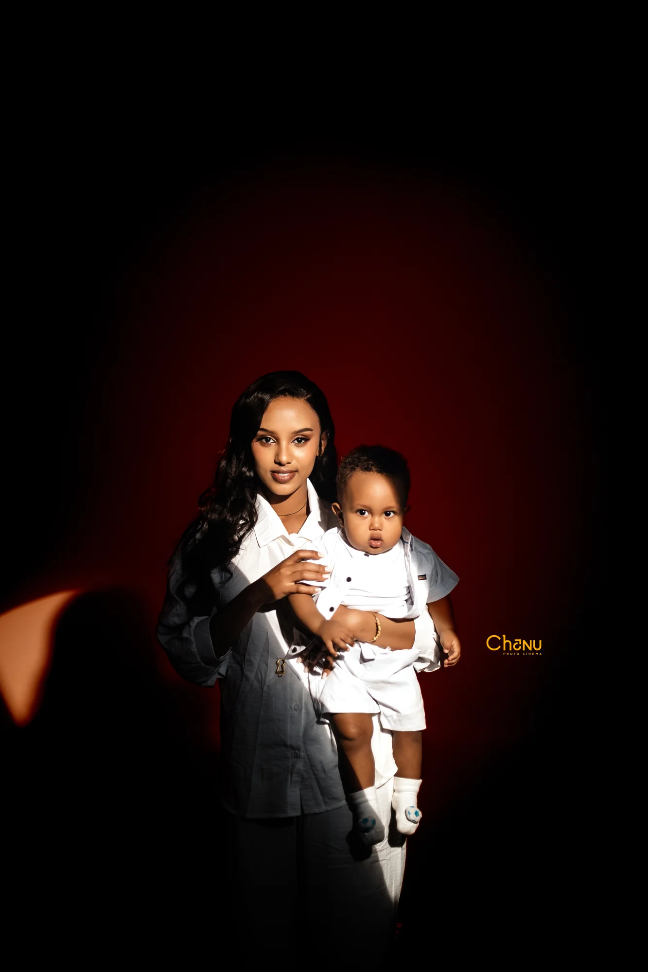 Dramatic chiaroscuro studio lighting portrait of mother and child in matching white