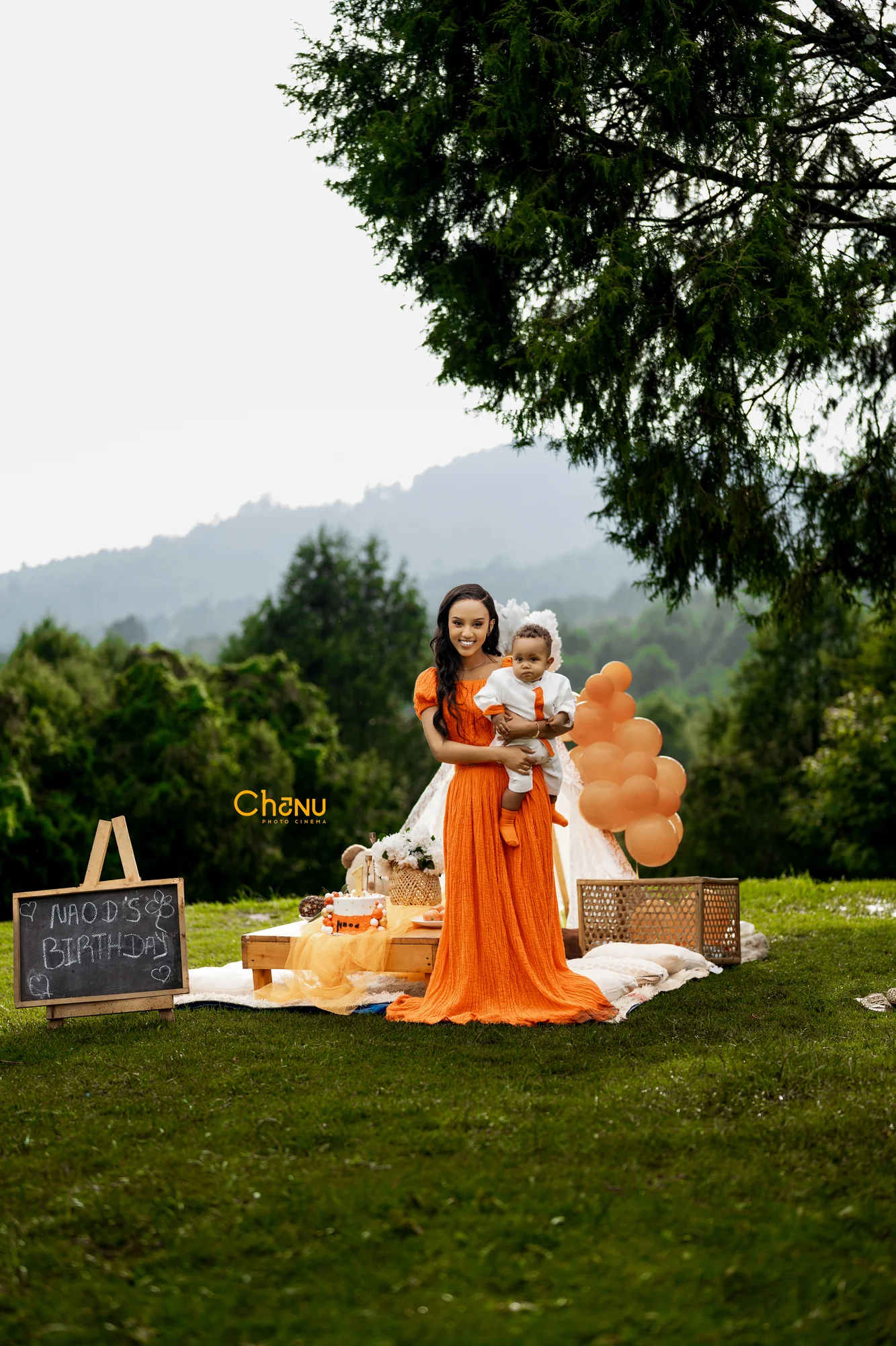 Naod's 1st birthday outdoor celebration on mountain hillside with lace teepee and chalkboard sign