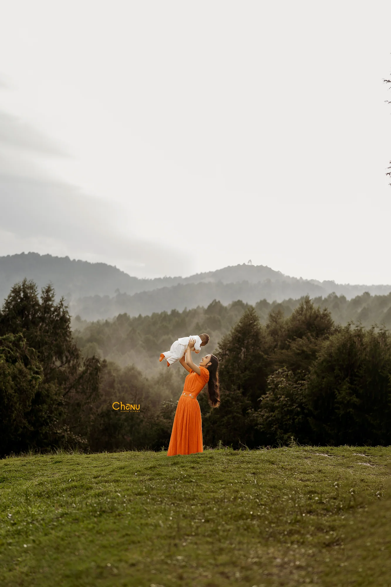 Mother lifting her baby in the air over scenic misty Ethiopian mountain ridge